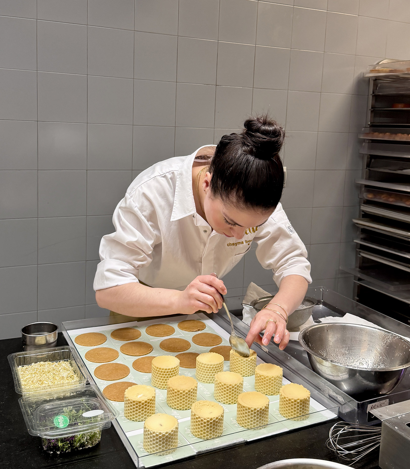 Pâtissière Chayma garnissant des cylindres de pâte feuilletée texturée en cuisine lors d'un concours